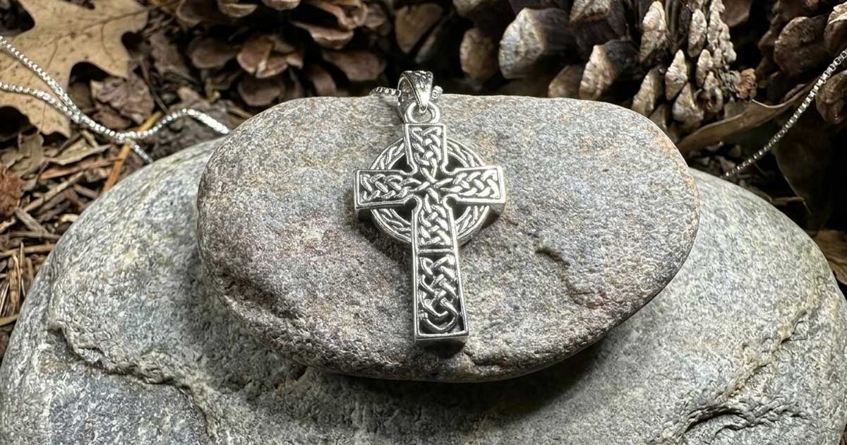 Celtic cross necklace pendant on natural stone background with traditional Irish knotwork design